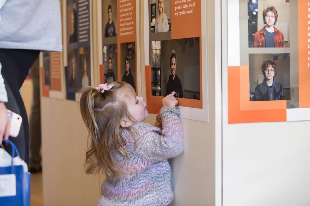 A little girl points to a photo in the exhibit